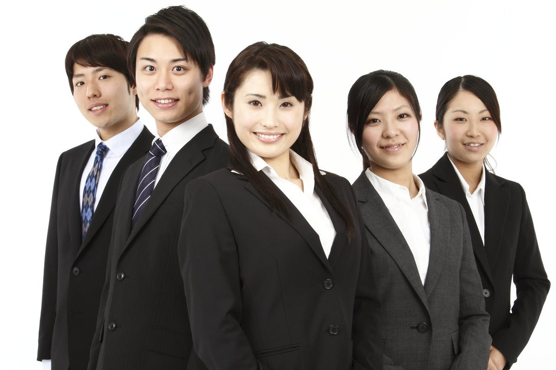 濃い色のスーツを着て並ぶ若い男女