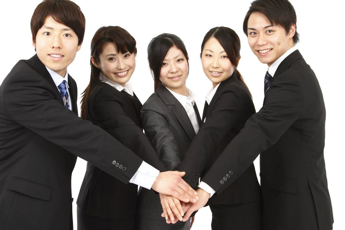 手を重ねる、スーツ姿の若い社員たち